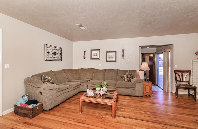 living room featuring light wood-type flooring and a textured ceiling