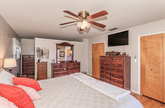 bedroom featuring ceiling fan, hardwood / wood-style floors, and a textured ceiling