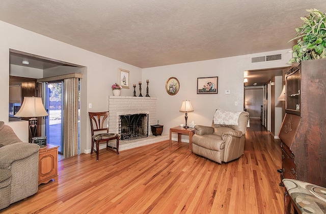 living room with light hardwood / wood-style floors, a textured ceiling, and a fireplace