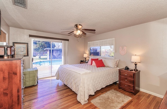 bedroom with ceiling fan, light hardwood / wood-style flooring, access to outside, and a textured ceiling