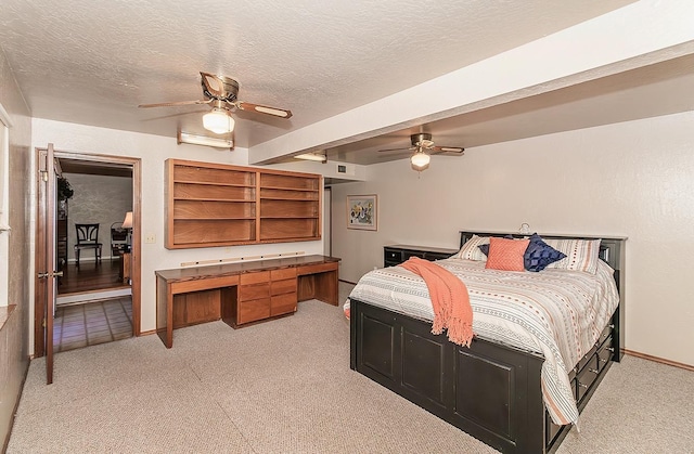 bedroom featuring a textured ceiling, light colored carpet, ceiling fan, and built in desk