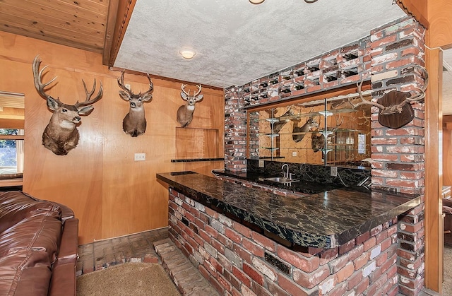 bar featuring sink, dark carpet, beam ceiling, and dark stone counters