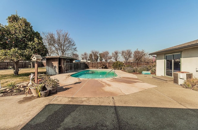 view of pool with a patio area, a shed, and central AC