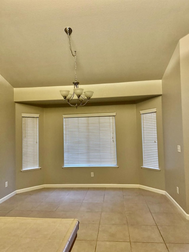 empty room with an inviting chandelier and tile patterned flooring