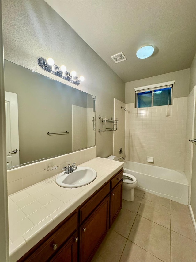 full bathroom with tile patterned floors, tiled shower / bath combo, toilet, a textured ceiling, and vanity