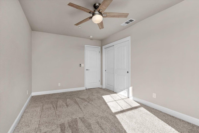 unfurnished bedroom featuring ceiling fan, light colored carpet, and a closet