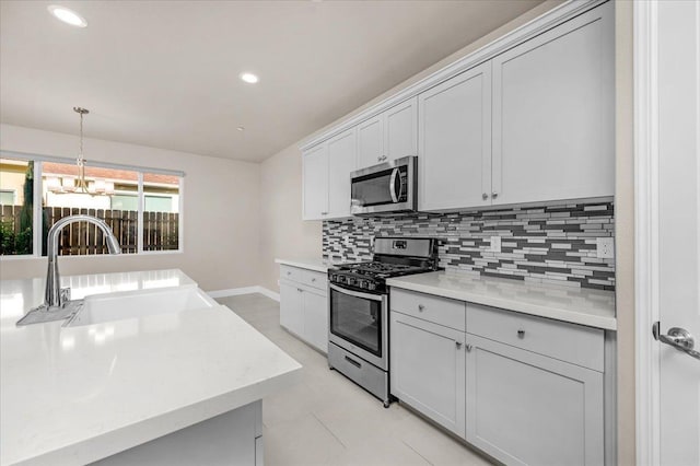 kitchen with sink, backsplash, stainless steel appliances, a notable chandelier, and decorative light fixtures