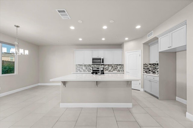 kitchen with sink, a center island with sink, backsplash, appliances with stainless steel finishes, and white cabinets