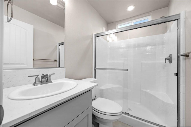 bathroom with toilet, vanity, and a shower with shower door