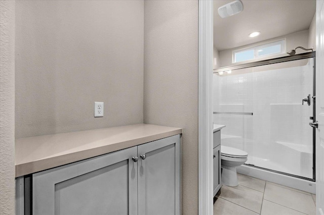 bathroom with vanity, a shower with shower door, tile patterned floors, and toilet