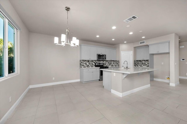 kitchen featuring sink, a center island with sink, appliances with stainless steel finishes, pendant lighting, and backsplash