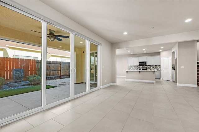 unfurnished living room featuring light tile patterned floors and ceiling fan