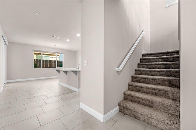 staircase with tile patterned flooring and a chandelier