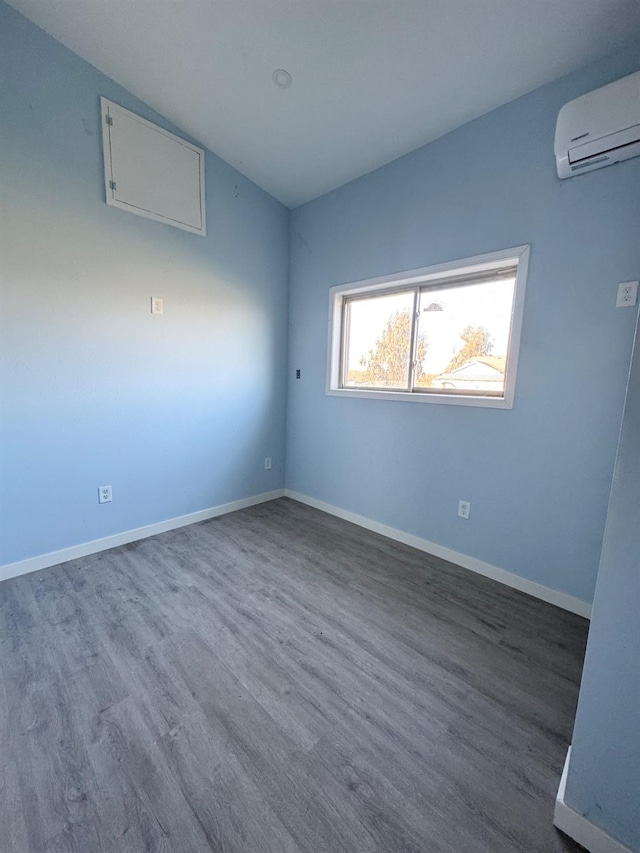 spare room featuring a wall mounted air conditioner, baseboards, lofted ceiling, and wood finished floors