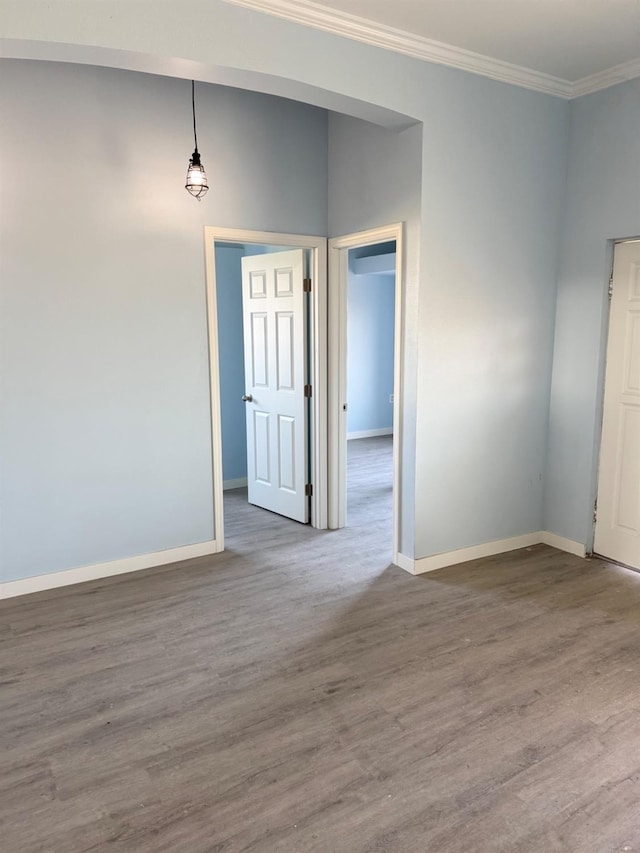 spare room featuring baseboards, wood finished floors, and ornamental molding