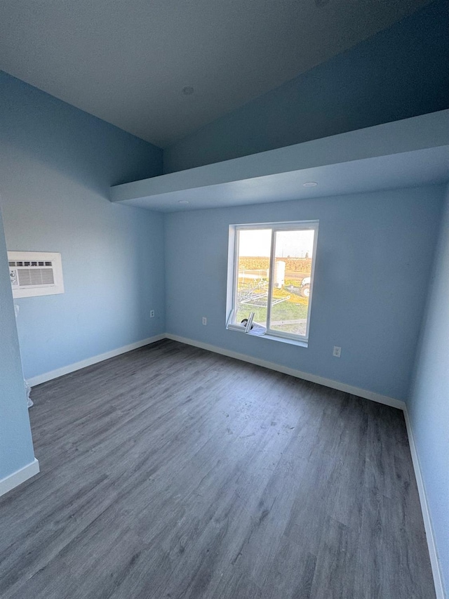 unfurnished room with baseboards, an AC wall unit, and dark wood finished floors