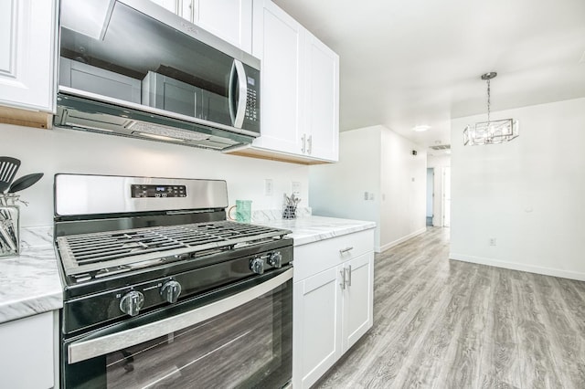 kitchen featuring light stone countertops, decorative light fixtures, stainless steel appliances, and white cabinets