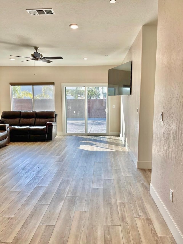 unfurnished living room with a healthy amount of sunlight, ceiling fan, and light hardwood / wood-style flooring