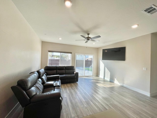 living room featuring ceiling fan, light hardwood / wood-style flooring, and a textured ceiling