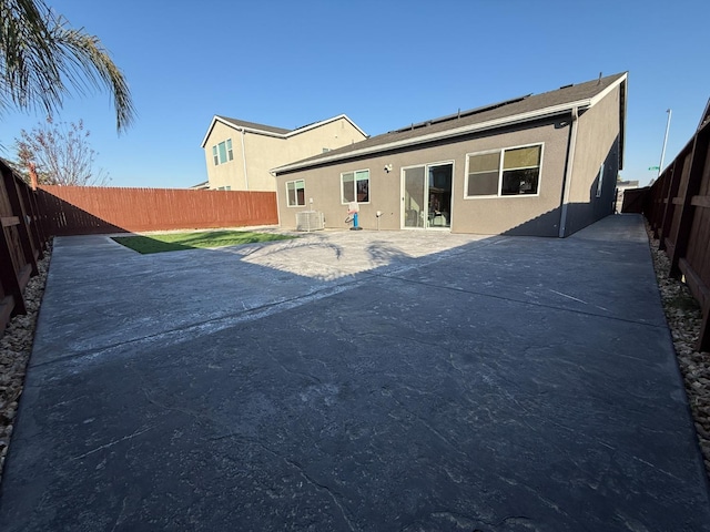 back of property with central AC and a patio