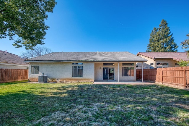 back of property with central AC unit, a lawn, and a patio