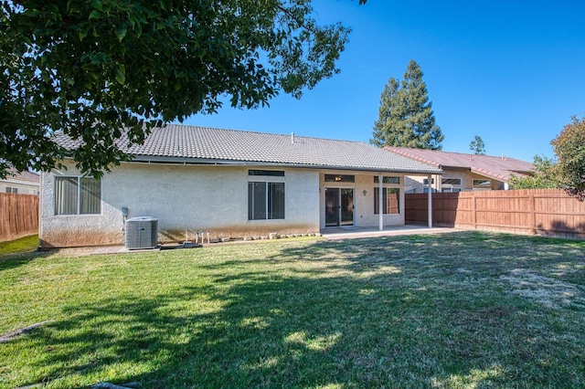 rear view of property featuring central air condition unit, a lawn, and a patio