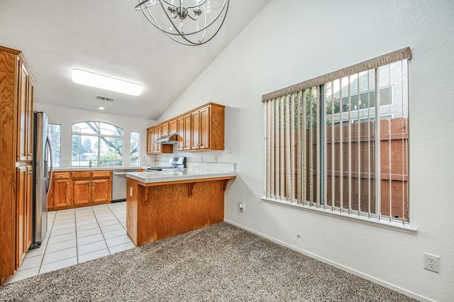 kitchen with a kitchen bar, vaulted ceiling, light carpet, kitchen peninsula, and stainless steel appliances