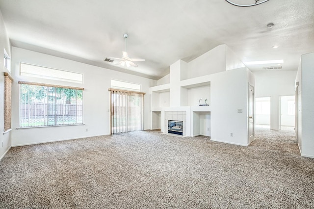 unfurnished living room featuring carpet flooring, a textured ceiling, a tiled fireplace, built in features, and ceiling fan