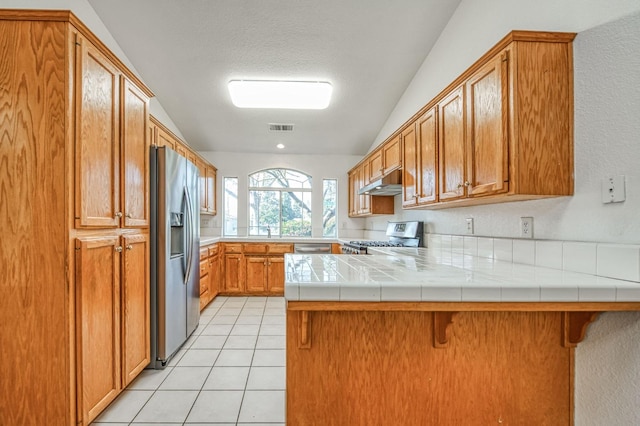 kitchen featuring a breakfast bar area, kitchen peninsula, range, and stainless steel fridge