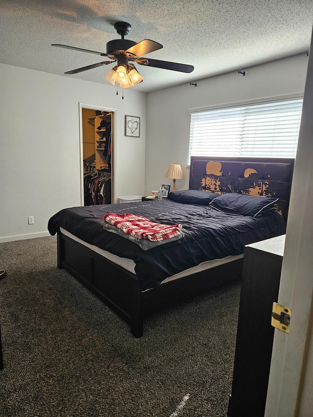 bedroom with a walk in closet, carpet, ceiling fan, a textured ceiling, and a closet