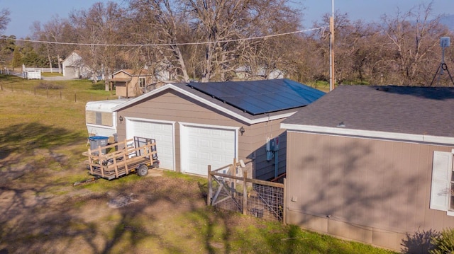 garage featuring a lawn and solar panels