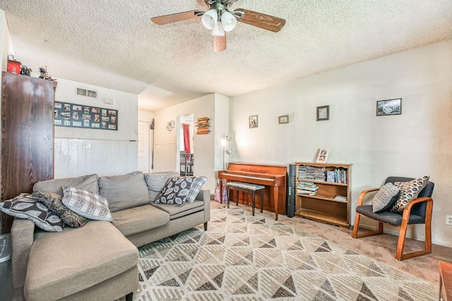 carpeted living room with a textured ceiling and ceiling fan