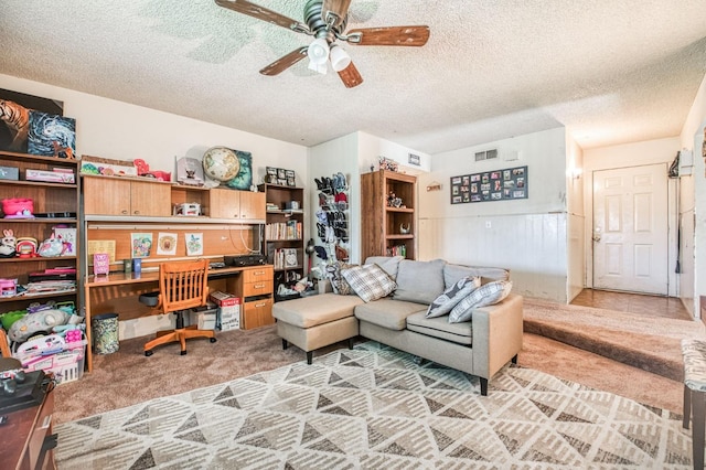 carpeted home office with ceiling fan and a textured ceiling