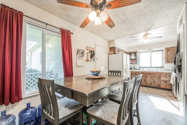 dining area featuring ceiling fan and a textured ceiling