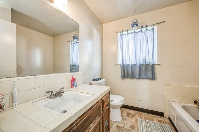 bathroom with toilet, decorative backsplash, a bathing tub, and vanity