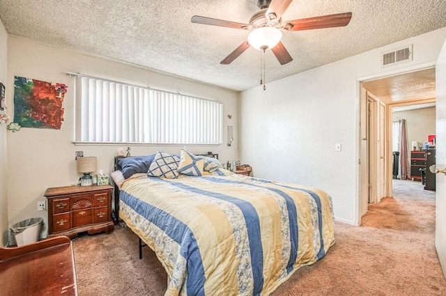 bedroom with ceiling fan, light colored carpet, and a textured ceiling