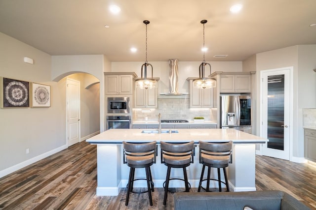 kitchen featuring pendant lighting, a kitchen island with sink, appliances with stainless steel finishes, and tasteful backsplash