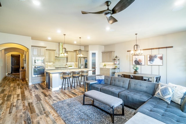 living room featuring ceiling fan with notable chandelier and dark hardwood / wood-style flooring