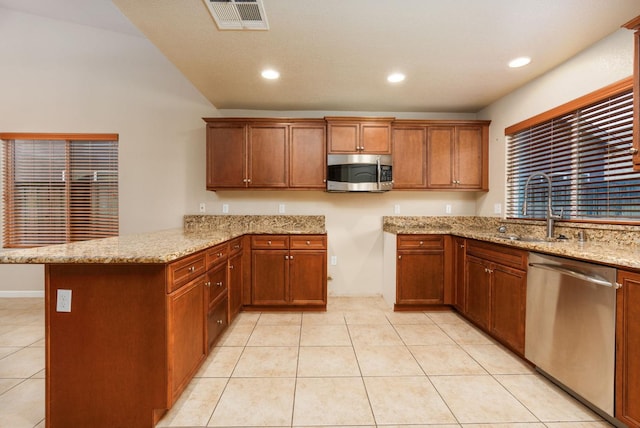 kitchen with kitchen peninsula, sink, light stone countertops, and stainless steel appliances