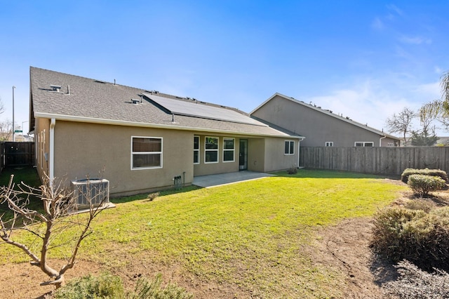 back of house featuring a patio, central AC unit, a lawn, and solar panels