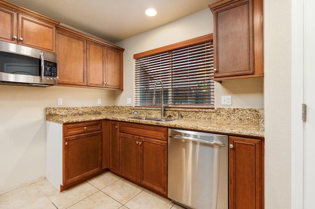 kitchen with sink, light stone counters, light tile patterned floors, and stainless steel appliances