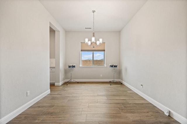 unfurnished dining area with hardwood / wood-style flooring and a notable chandelier