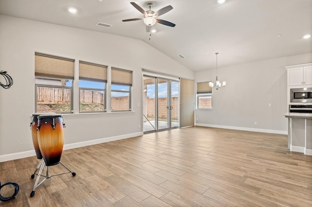 unfurnished living room featuring ceiling fan with notable chandelier, vaulted ceiling, and light hardwood / wood-style floors