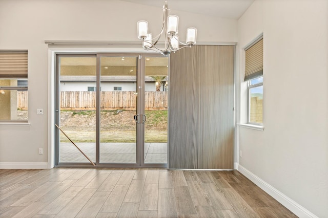 doorway with lofted ceiling, hardwood / wood-style floors, and a chandelier