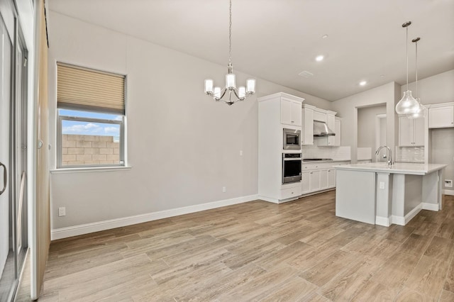 kitchen featuring stainless steel appliances, white cabinetry, a kitchen island with sink, and pendant lighting