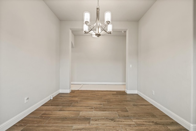 unfurnished dining area with dark hardwood / wood-style flooring and a chandelier