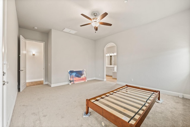 unfurnished bedroom featuring ceiling fan, ensuite bath, and light carpet