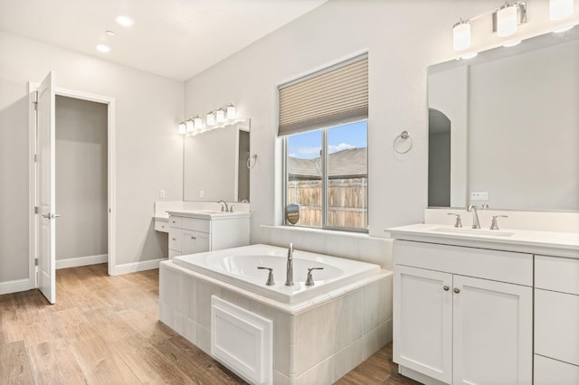 bathroom featuring vanity, hardwood / wood-style floors, and a relaxing tiled tub