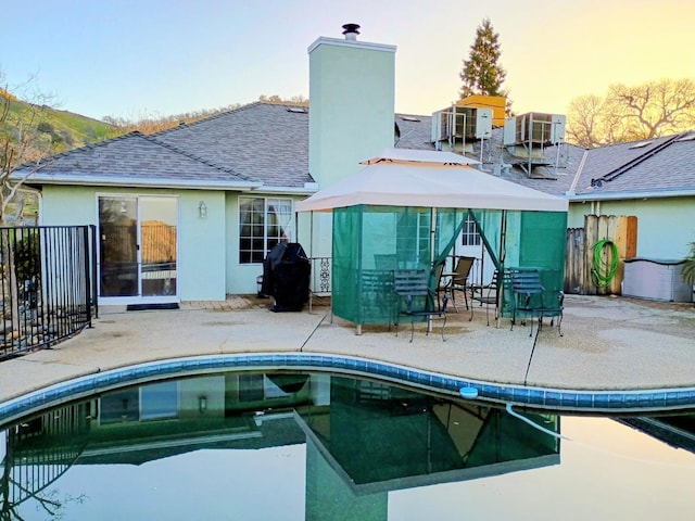 back house at dusk featuring cooling unit and a patio area