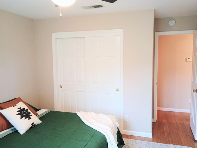bedroom featuring visible vents, a closet, baseboards, and wood finished floors
